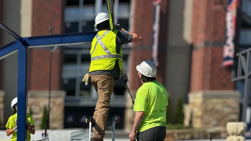 Crew members in hard hats and safety vests assembling an elevated steel-railed structure.