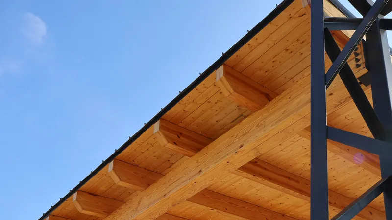 The wood-decked underside of a steel-framed pavilion roof, viewed from below.